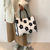A woman holds a white faux fur leopard print tote bag against a light background.