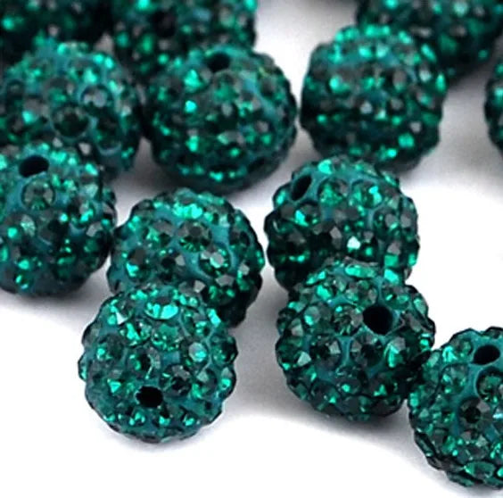 A close-up of small, round, textured teal crystal clay beads scattered on a white background.