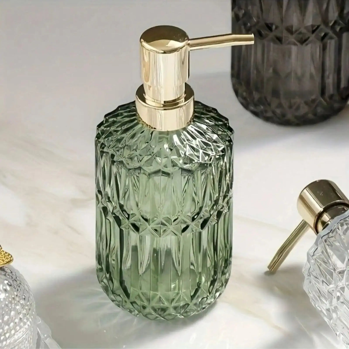 A clear green textured glass soap dispenser with a gold pump top sitting on a white marble surface.