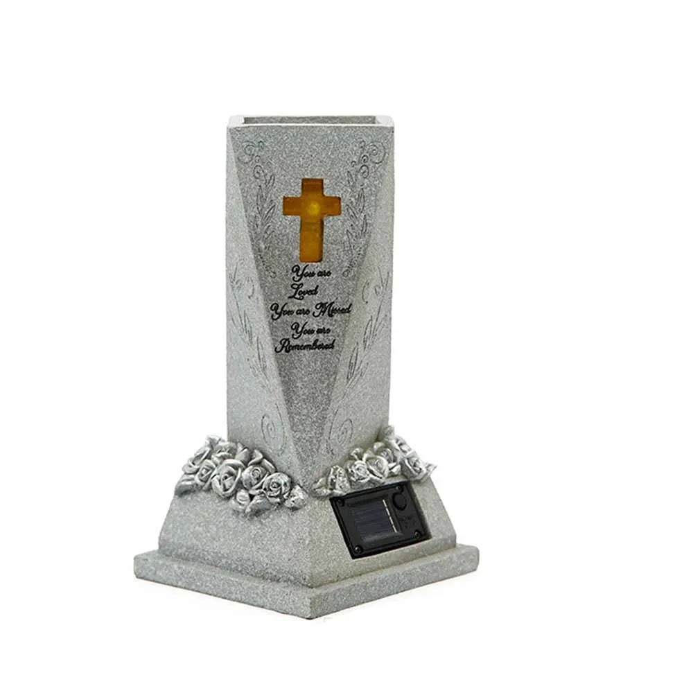 A silver memorial vase with a cross engraved on it and adorned with floral accents.