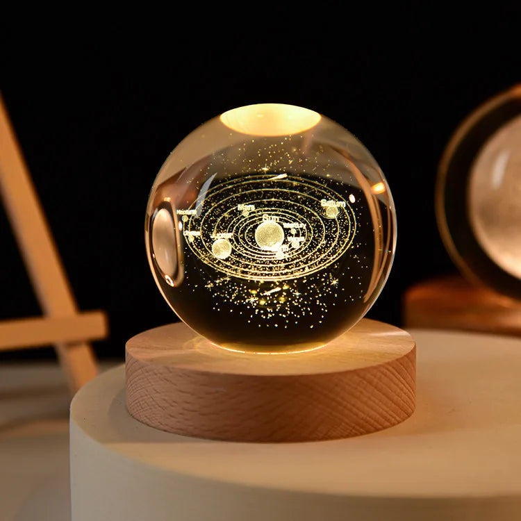 A glowing crystal ball with laser engraved patterns rests on a wooden base.