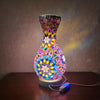 A handcrafted Turkish mosaic table lamp with a vibrant, colorful glass base and a metallic top, illuminated by a warm LED glo