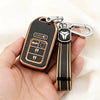 A black and gold TPU protective key case with a silver clip is held in a hand.