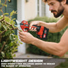 A man uses a red cordless electric pruning shear tool on a green shrub.