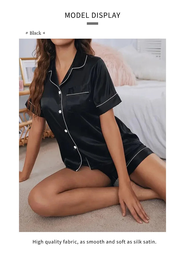 A model wearing a black satin pajama set with a button-down top and shorts, displayed in a studio setting.