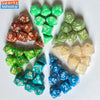 A set of seven polyhedral dice in various shades of green and amber resting on a white surface.