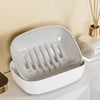 A white double-layer draining soap dish with a non-slip base is shown on a light surface.