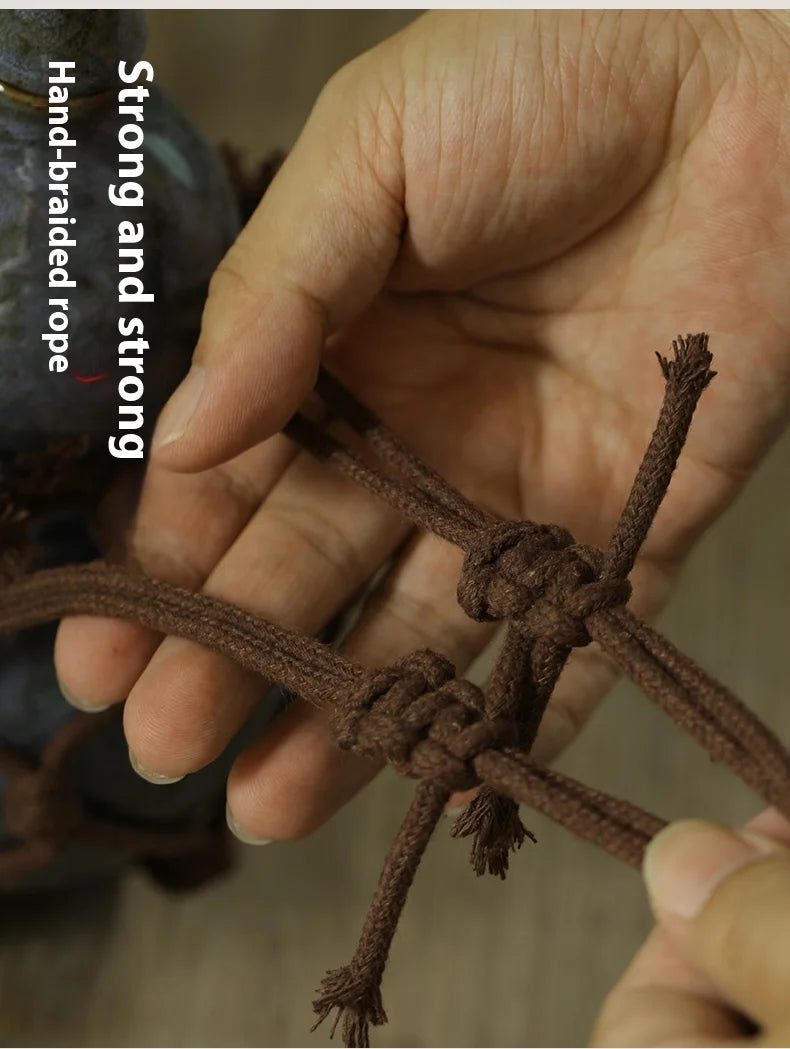 A hand is holding a piece of dark brown braided rope, demonstrating its strength.