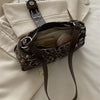 A brown leopard print PU leather shoulder bag with a dark brown strap is shown resting on a light beige fabric.