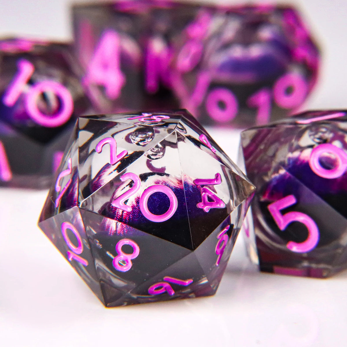 A close-up of a set of liquid core resin dice with a dragon eye design, showing various numbers and purple accents.