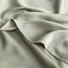 A close-up of a light beige luxury bamboo flat sheet fabric draped softly.