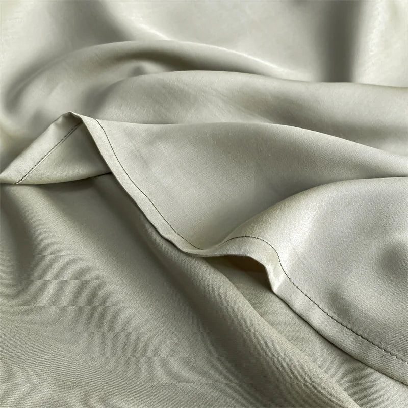 A close-up of a light beige luxury bamboo flat sheet fabric draped softly.