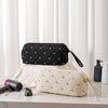 Two fabric storage bags, one black and one beige, are displayed on a white surface next to a hair dryer.