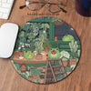 A round desk mat featuring a kawaii nature design of various green frogs and potted plants.
