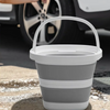 A white collapsible bucket sitting on a concrete surface with a car wheel in the background.