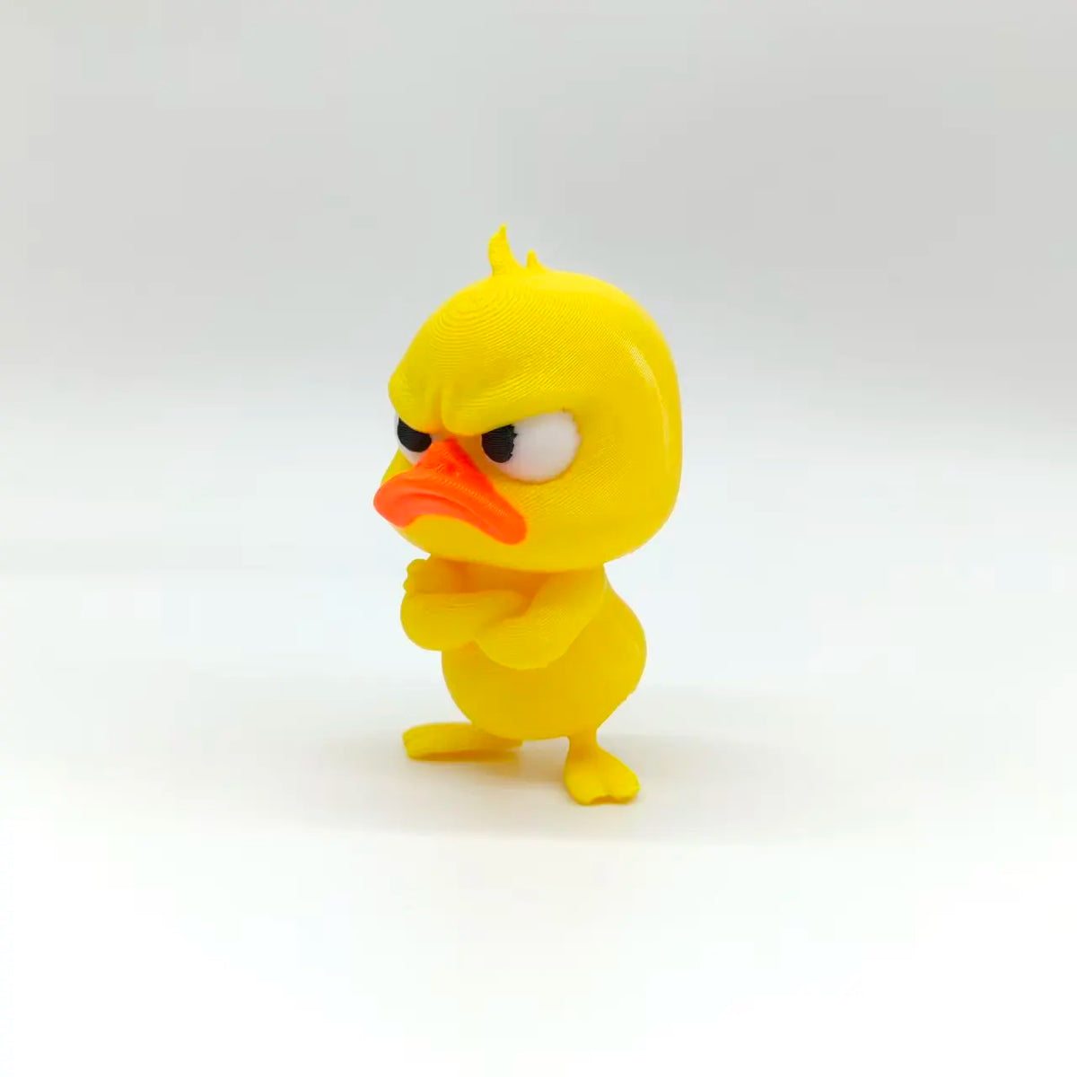 A yellow, stylized duck statue with an angry expression and orange beak.