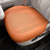 An orange breathable leather car seat cushion is shown placed in the interior of a vehicle.