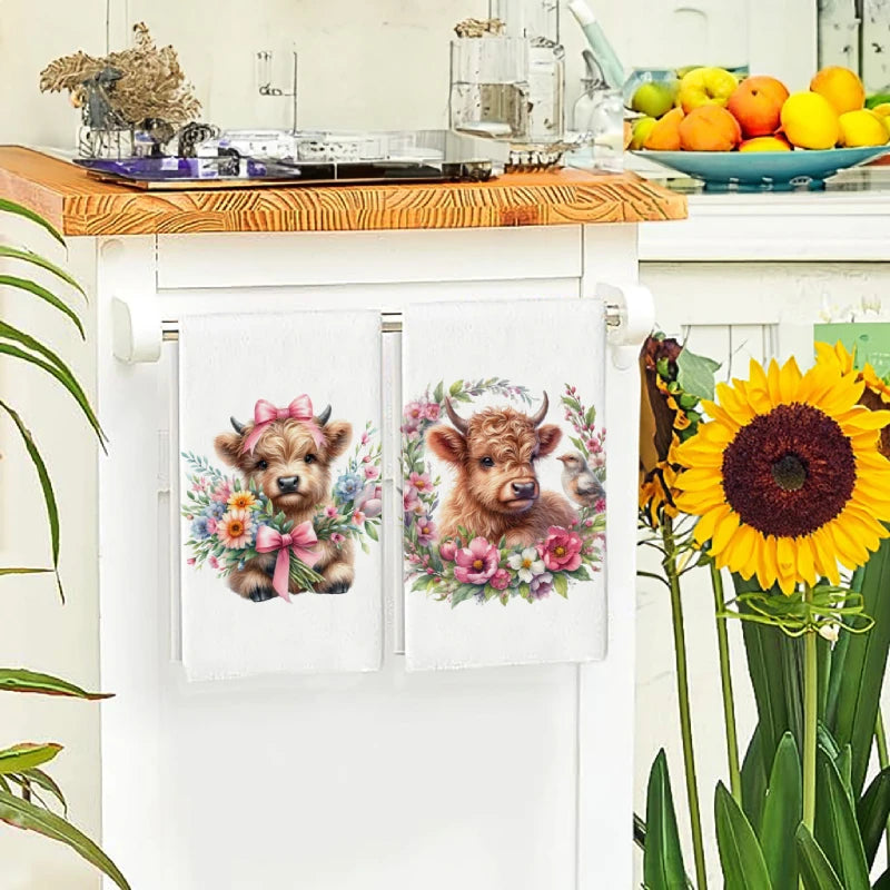 A set of two embroidered kitchen towels featuring cute Highland cows surrounded by colorful flowers.