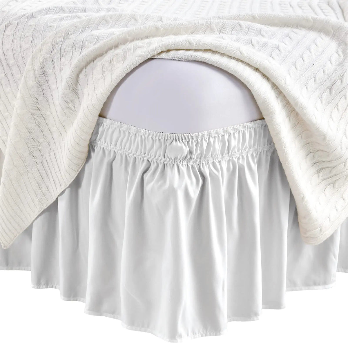 White elastic wrap-around bed skirt with ruffles draped over a pregnant belly
