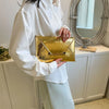 A person wearing a white shirt holds a gold crocodile pattern PU envelope clutch with a coin pocket.