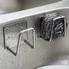 Stainless steel sponge holder with a mesh scrubber attached, mounted on a sink surface.