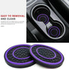 A set of two non-slip silicone car cup holder coasters with purple accents shown next to a car interior component.