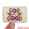 A beige embroidered patch featuring the letters G O D surrounded by pink and blue floral designs.