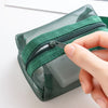 A hand is opening a transparent mesh storage bag with a green zipper to view its contents.