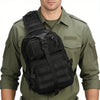 A man wearing a olive green shirt is holding a black Crossbody Chest Bag with multiple zipper compartments and a MOLLE system