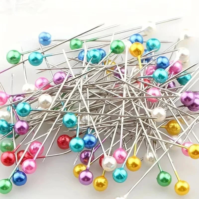 A collection of pearlized ball head sewing pins in various colors like blue, green, pink, and gold.