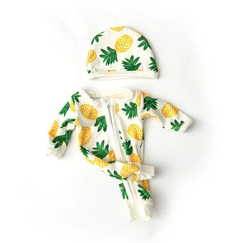 A white and yellow patterned jumpsuit outfit for a baby doll featuring a matching hat.