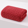 A folded, deep red, textured bath towel with a diamond pattern.