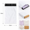 A white self-sealing mailing bag with a black plaid seal and a purple shirt inside, shown next to a folded garment.