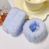 A stack of light blue microfiber wrist sweatbands and scrunchies for face washing placed next to a yellow bowl.