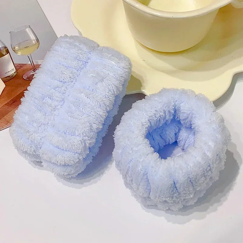 A stack of light blue microfiber wrist sweatbands and scrunchies for face washing placed next to a yellow bowl.