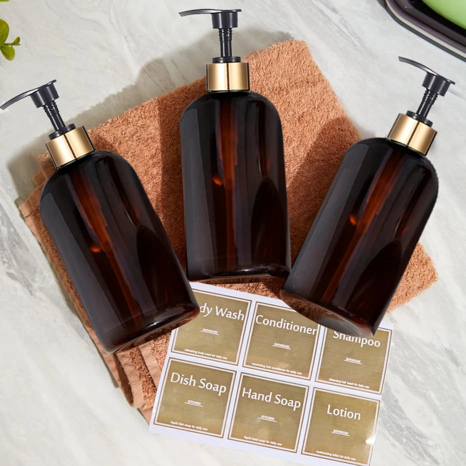 A collection of dark amber refillable gold pump soap dispenser bottles resting on a brown towel and product labels.