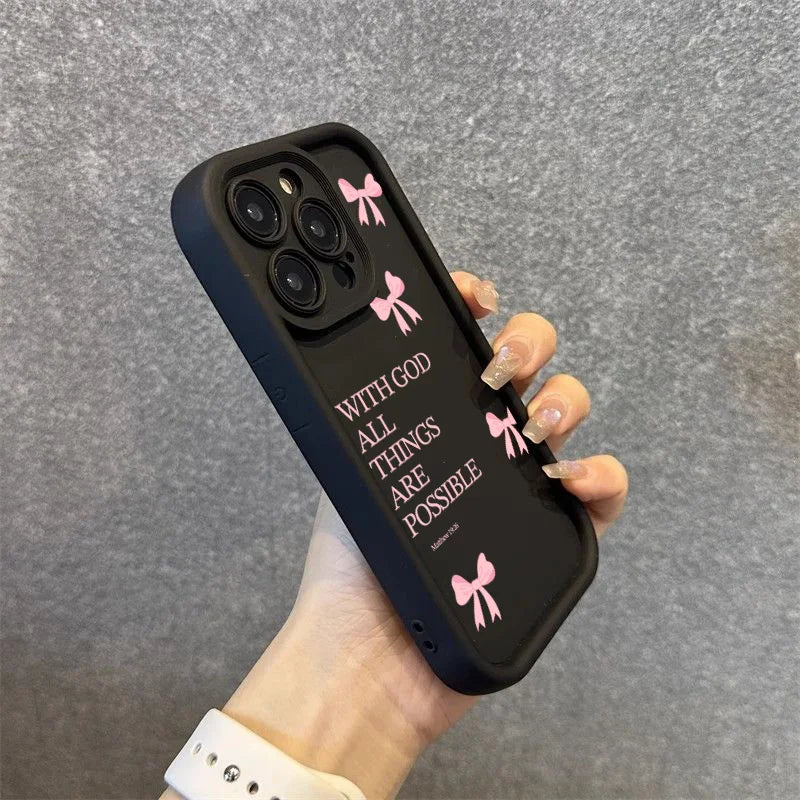 A hand holds a black silicone phone case with pink bow slogans on an iPhone.