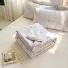 A stack of white and lavender lace-trimmed breathable summer duvet pillows with a floral pattern.