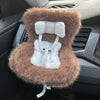 A miniature doll seat car vent decoration covered in fluffy brown faux fur with a white trim and tie.