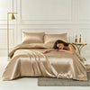 A luxurious champagne silk duvet cover set displayed on a bed with a gold floor lamp.