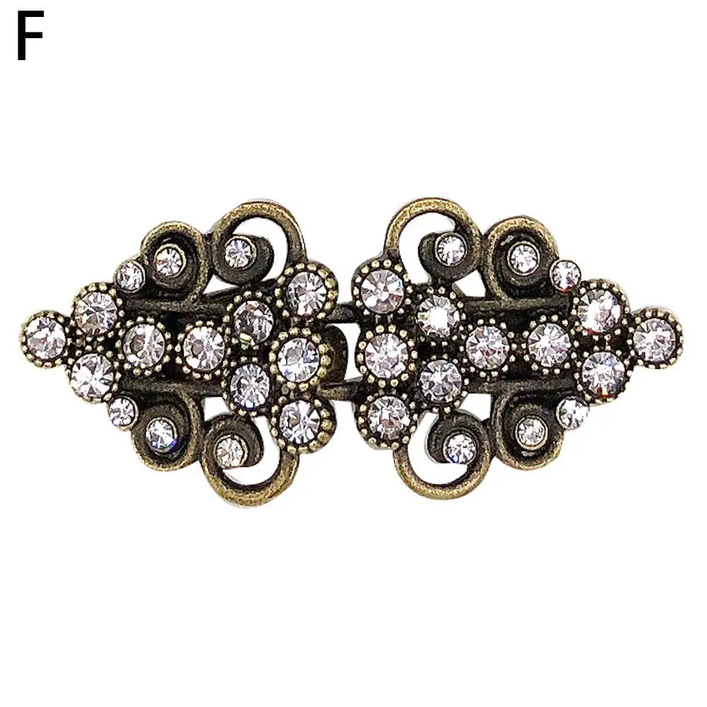 Vintage gold-toned swirl clip featuring clear rhinestones for holding sweaters and cardigans