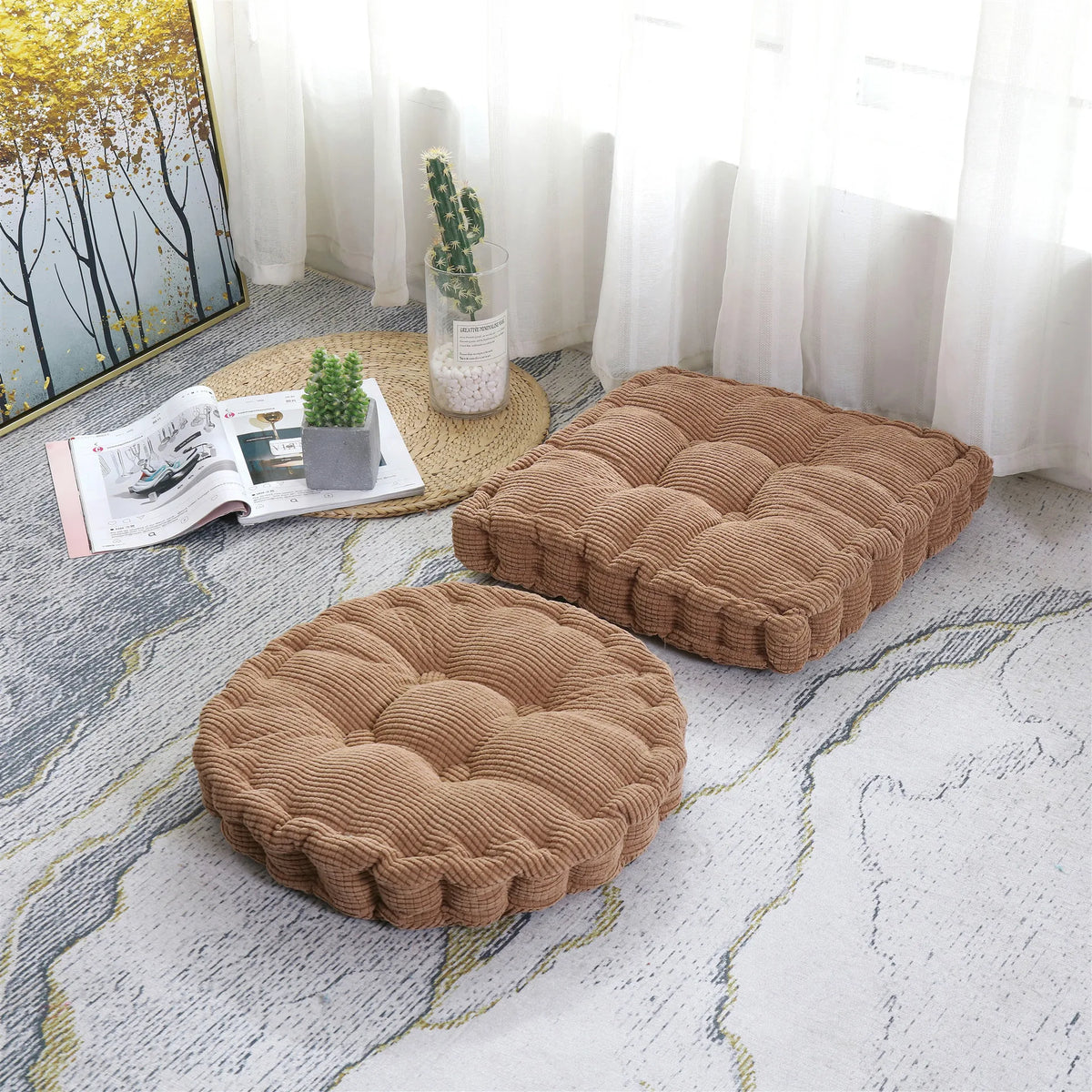A beige corduroy floor cushion is placed on a light gray rug next to a window with sheer white curtains.