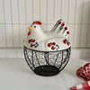 A white ceramic hen-shaped egg basket with a lid and black wire mesh bottom