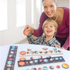 A smiling woman holds a wooden solar system puzzle with colorful planets and moons for children.