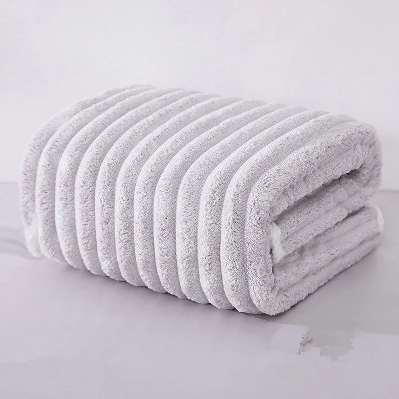 A stack of white microfiber towels rolled into a cylinder, showing their soft texture and ribbed design.