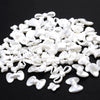 A pile of 100 white acrylic pearl spacer beads in various bow and flower shapes for jewelry making