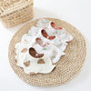 A stack of six-layer cotton baby feeding bibs with absorbent drool towels resting on a woven mat.