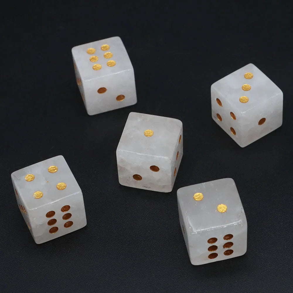 Five natural stone dice showing various patterns and colors like gold, brown, and white on a dark surface.