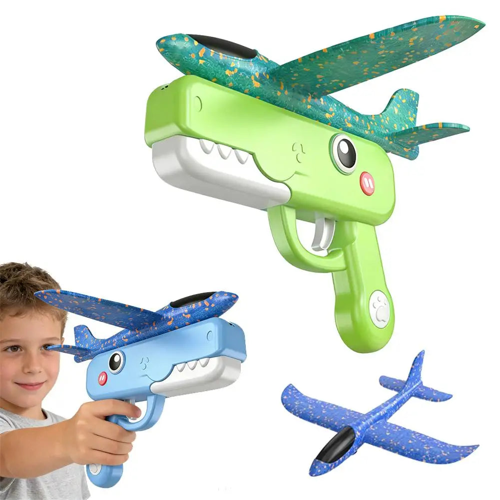 A green foam catapult toy shaped like a dinosaur with an attached airplane wing is shown next to a child's hand.