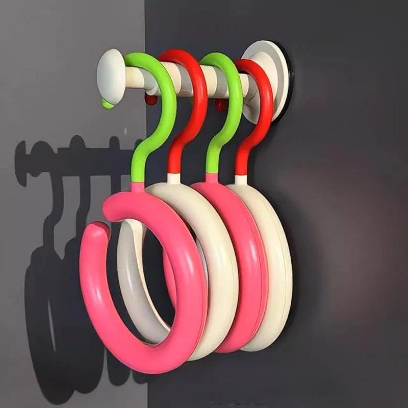 A wall-mounted organizer hook with multiple colored plastic rings for hanging hats and scarves.